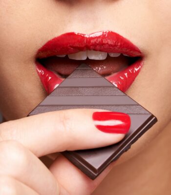 Closeup portrait of a cute young female biting into a piece of chocolate
