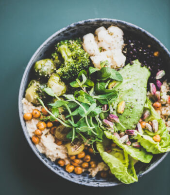 Healthy vegan championship game and green smoothie on dark background Healthy dinner or lunch at home. Vegan championship game or Buddha bowl with hummus, vegetable, fresh salad, beans, couscous and avocado on dark background, top view