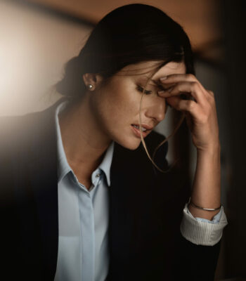 Shot of a young businesswoman experiencing stress during a late night in a modern office